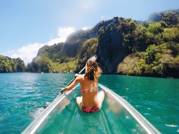 Rear view of woman sitting on swimming pool against sea