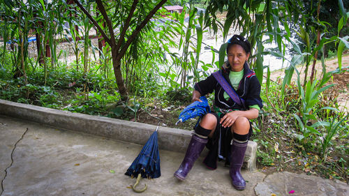 Full length of teenage girl sitting on seat against trees