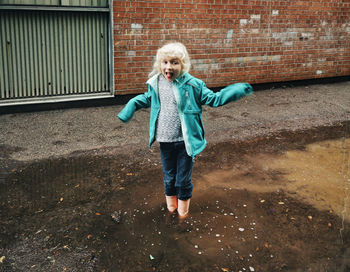 Girl standing in dirty puddle against wall