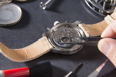 Cropped hand of craftsperson repairing wristwatch at desk