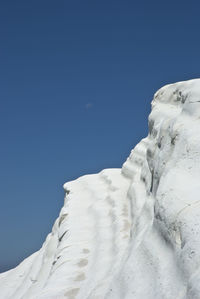 Low angle view of snow against clear blue sky