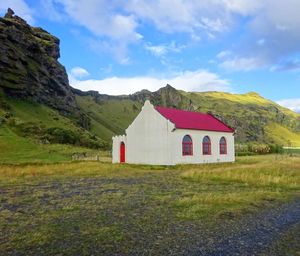 Built structure on field by mountain against sky