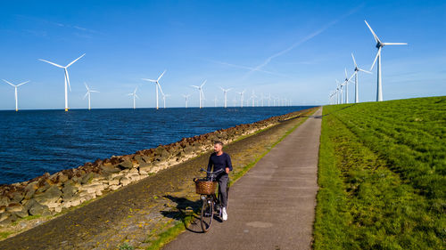 Rear view of man walking on road against clear sky