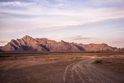 Scenic view of field with round directing going to the mountain against sky