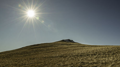 Low angle view of sun shining over mountain