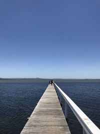 Pier over sea against clear blue sky