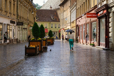 Rear view of man walking on street amidst buildings