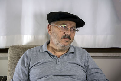 Young man looking away while sitting on sofa at home