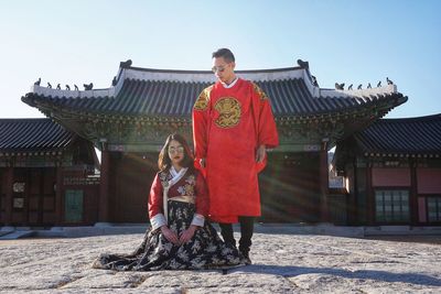 Friends wearing traditional clothing against historic building