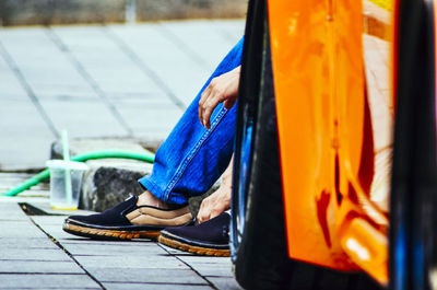 Low section of person sitting on footpath