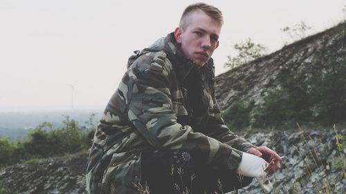 Portrait of army soldier crouching on mountain