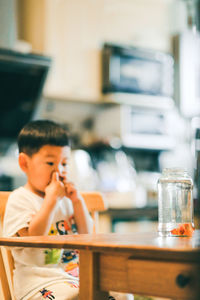 Boy sitting on table at home