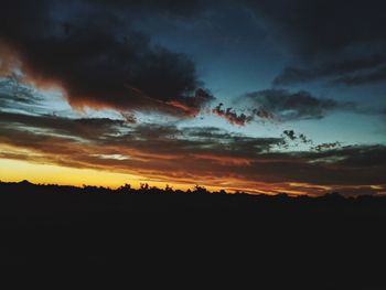 Silhouette landscape against dramatic sky during sunset