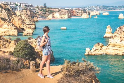 Woman standing on rock by sea