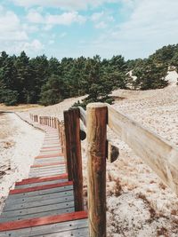 Wooden posts on footpath amidst field against sky