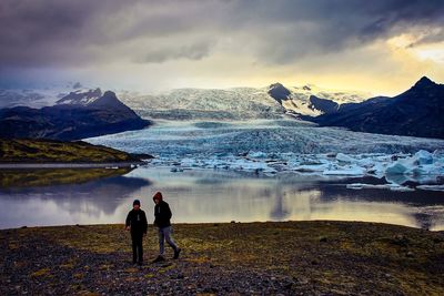 Friends walking at frozen beach against sky