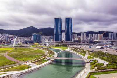 South korea, busan, cloudy sky over bridge over river flowing through city park