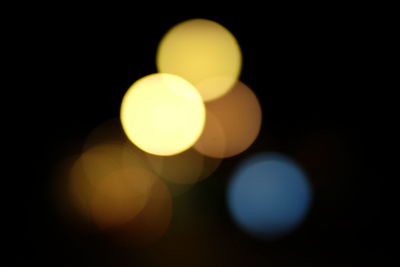 Defocused image of illuminated lights against sky at night