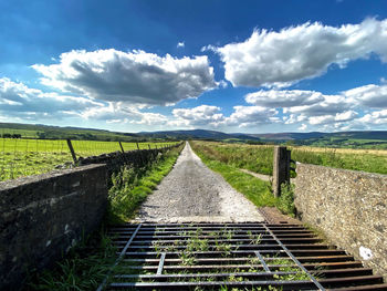 Farm road, with a cattle grid, fields, and distant hills near, newton, clitheroe, uk