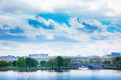 Arch bridge over river in city against sky