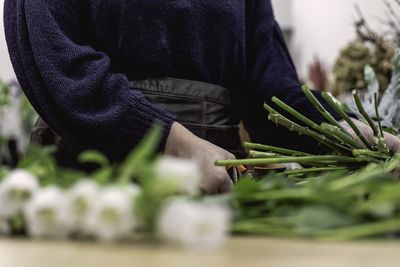 Female florist cutting stem of flower in workshop