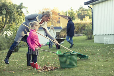 Mother and daughter raking autumn leaves at yard