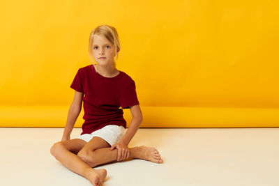 Portrait of young woman sitting on hardwood floor at home