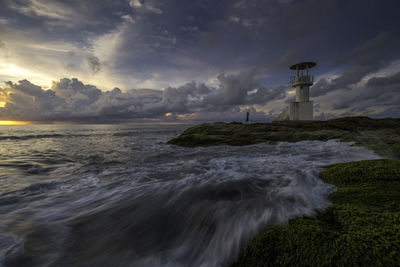 Lighthouse by sea against sky