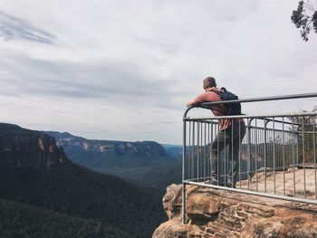 People standing by railing against mountains