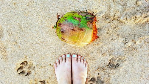 Low section of woman standing on sand at beach