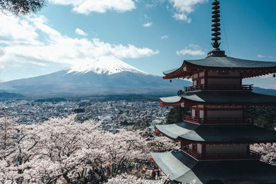 Traditional building by snowcapped mountain against sky