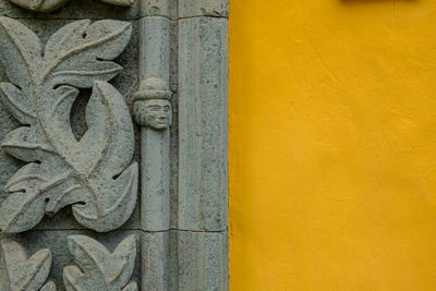 Low angle view of statue against yellow wall