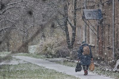 Rear view of man walking on snow covered road