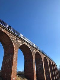 Low angle view of arch bridge against clear blue sky