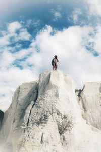 Low angle view of woman on white rock formation against sky