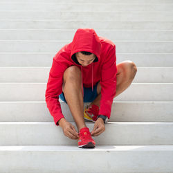 Low section of man sitting on staircase against wall