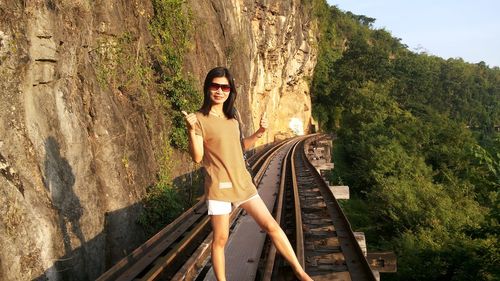 Portrait of smiling mature woman showing thumbs up standing on railway bridge 