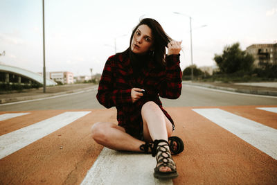 Portrait of young woman sitting on road