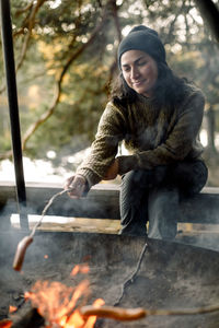 Woman roasting food over campfire during camping