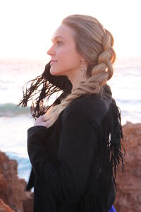 Young woman standing at beach against sky