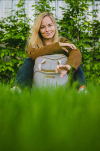 Portrait of smiling young woman with blond hair sitting on grass