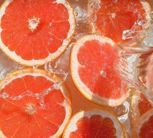 Close up view of the red grapefruit slices in lemonade background.  cooling sweet summer's drink. 