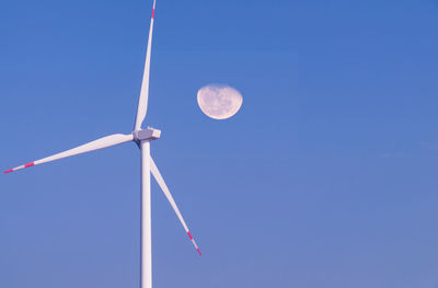 Low angle view of wind turbine against clear blue sky