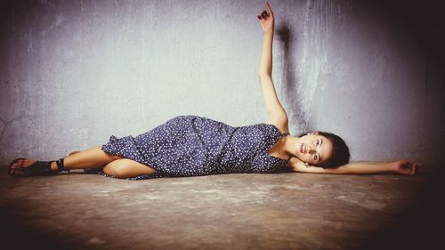 Woman lying on floor against wall