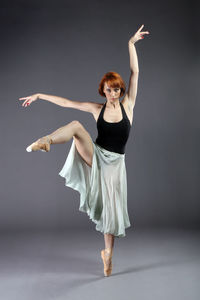 Portrait of ballet dancer dancing against gray background