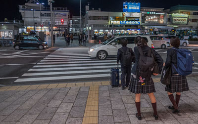 Rear view of people crossing road in city