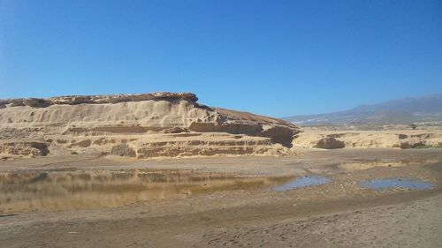 Scenic view of desert against clear blue sky