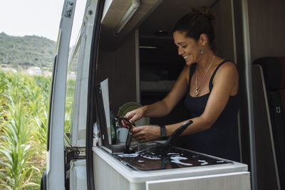 Woman with earrings washing dishes in motorhome during a vacation.