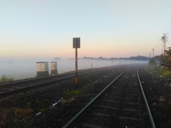 Railroad tracks against clear sky during sunset