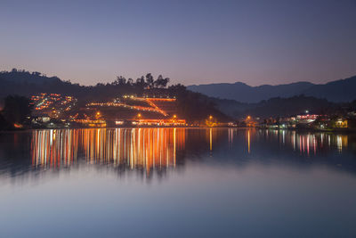 Scenic view of illuminated city against clear sky during sunset